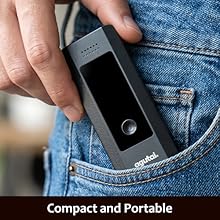 Text reads: 'Compact and Portable'. Black portable device with circular display held against denim jeans pocket, showing compact size and wearable form factor.